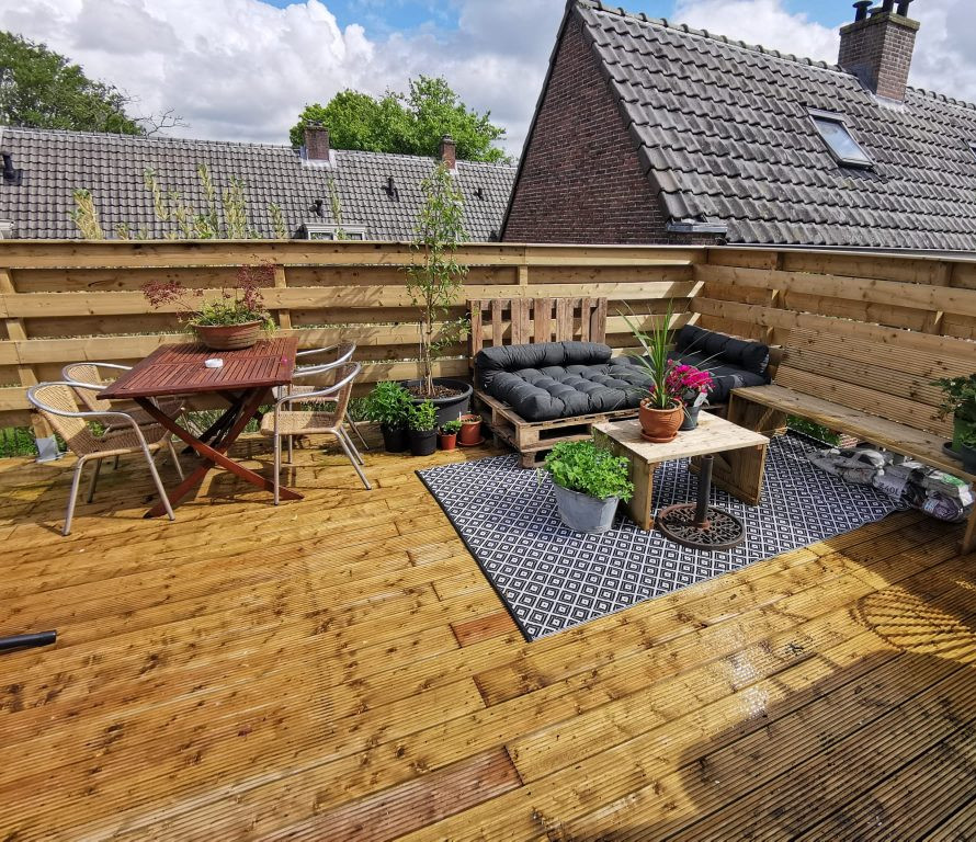 Dakterras met houten vlonder, palletbank en schutting rondom