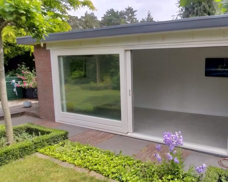 Tuinkamer met witte schuifpui en gestucte wanden, uitkijkend op de tuin